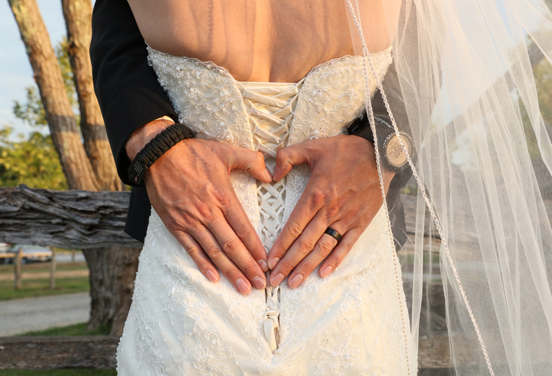 Wedding photography, a close-up shot of the groom's hands on the bride's back, in the shape of a heart. 