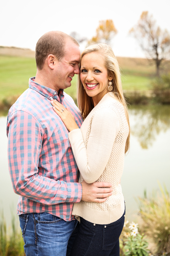Engagement photography, a couple embraces playfully as the young lady smiles at the camera. 