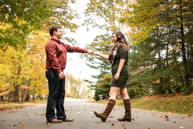 Engagement photography: a young man in jeans and red shirt twirls his fiancé. 