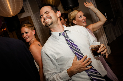 Wedding photography, a friend dances hilariously with the bride and bridesmaid. 