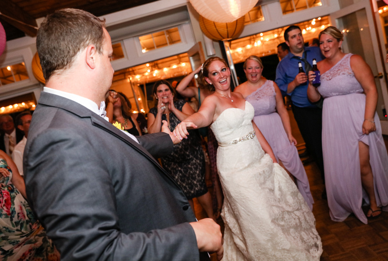 Wedding photography, the groom spins his bride on the dance floor. The guests are cheering them on. 