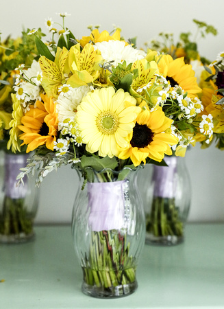 Wedding photography, a glass vase with a bouquet of yellow sunflowers and white daisies. 