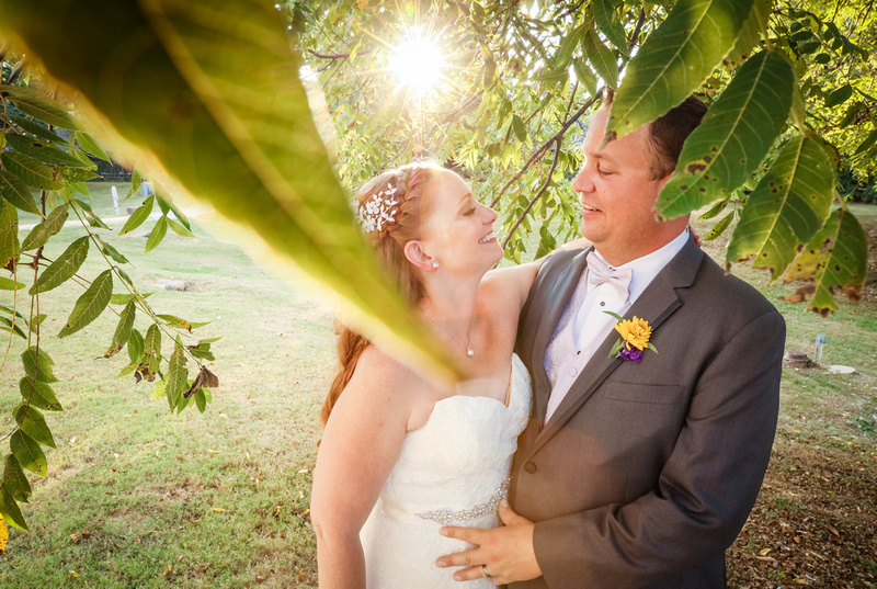 Wedding photography, the bride and groom are nestled under a tree and share a romantic look. 