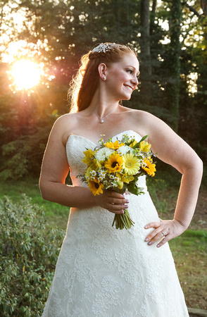 Wedding photography, the bride smiles while holding her bouquet of sunflowers and white daisies. 