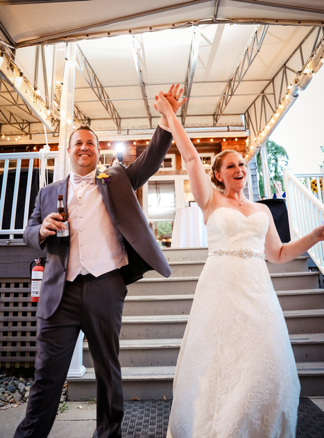 Wedding photography, a bride and groom make their grand entrance with their arms up in the air. 