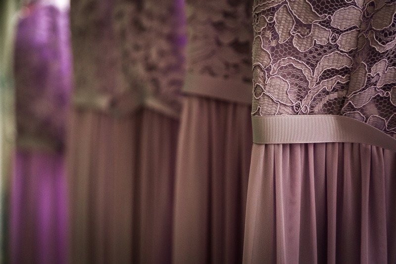 Wedding photography, lavender bridesmaids dresses with lace and ribbon hang in a row. 