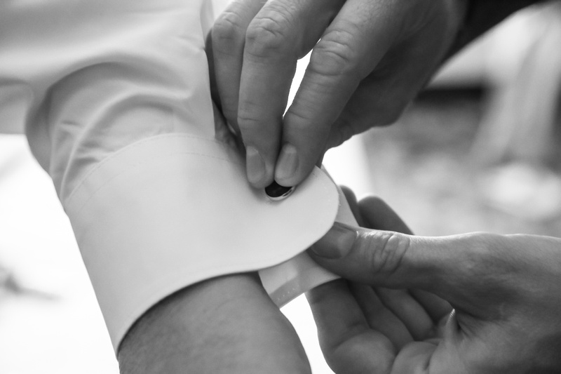 Wedding photography, a close-up of a groom putting on his cuff links. 