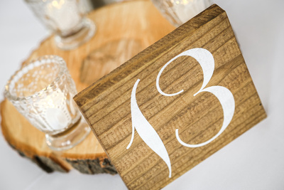 Wedding photography, the guest tables are numbered on rustic wooden slabs with white tea candles. 