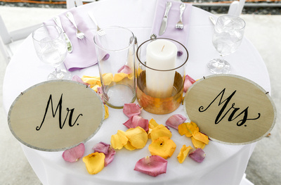 Wedding photography, the sweetheart table is set with white pilar candles and flower petals. 