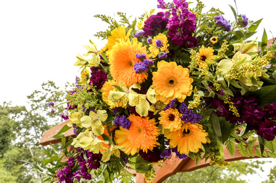 Wedding photography, a bouquet of yellow and purple flowers dons the arbor. 