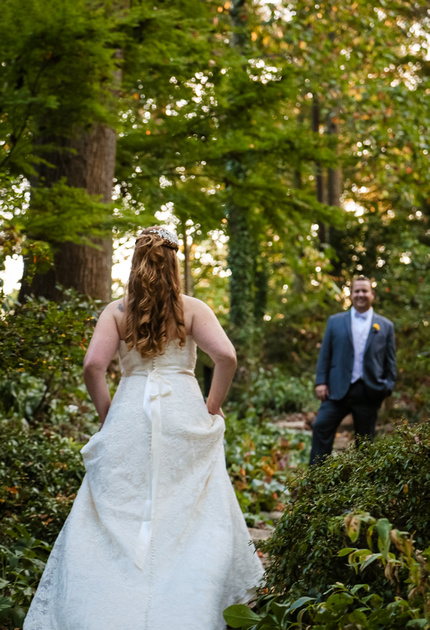 Wedding photography, the bride holds up her dress and walks through the forest to meet her groom. 