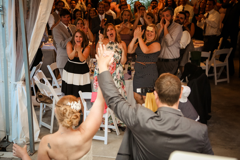 Wedding photography, the bride and groom enter their reception tent, their guests go wild. 