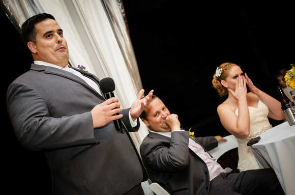 Wedding photography, the best man gives his speech while the bride and groom laugh. 
