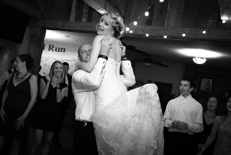 Wedding photography, the groom lifts the bride up into the air on the dance floor, she has a huge smile on her face. 