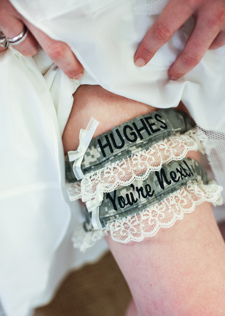 Wedding photography, a bride pulls up her dress to show two garters on her right leg. 