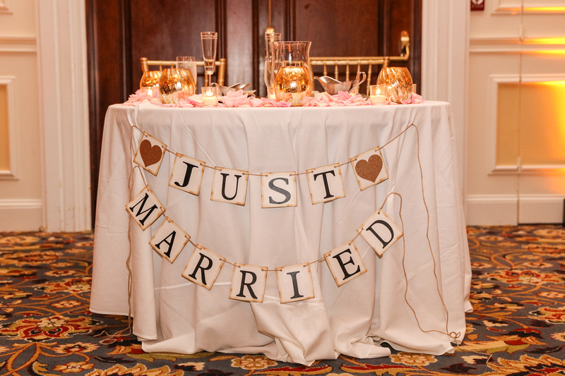 Wedding photography, a sweetheart table with white linen and gold adornments. It says, Just Married. 