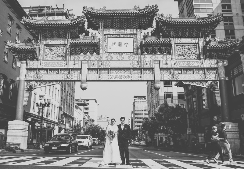 Wedding photography, a bride and groom stand in a crosswalk underneath the Chinatown arch. 