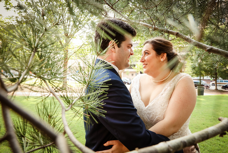 Wedding photography, a bride and groom gaze at each other romantically in an evergreen tree. 