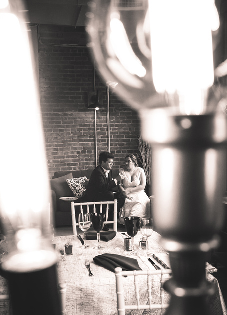 Wedding photography, a far away shot of a bride and groom sitting on a couch.