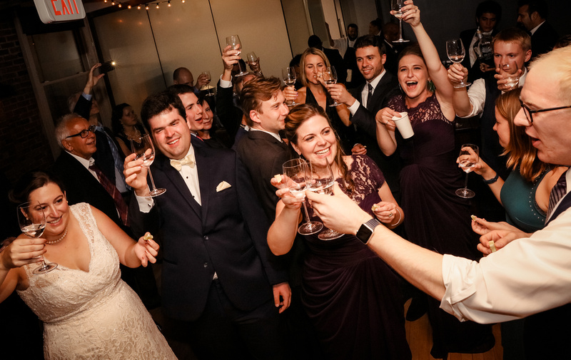 Wedding photography, happy wedding guests raise a glass and share a shot. 
