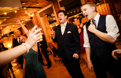 Wedding photography, a groom sings his heart out while dancing with friends. 