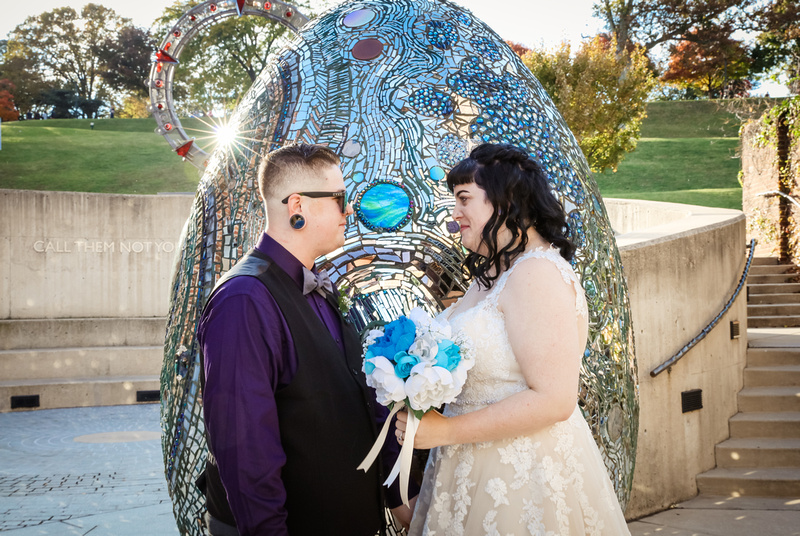 Wedding photography, a bride and groom smile lovingly. She is holding a bouquet of blue paper flowers. 