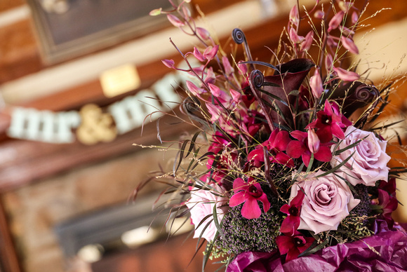 Wedding photography, a bouquet of purple and lavender flowers on a table. A Mr. and Mrs. sign is in the background. 