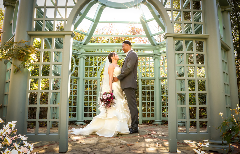 Wedding photography, the sun shining on a bride and groom embracing in a teal gazebo. 