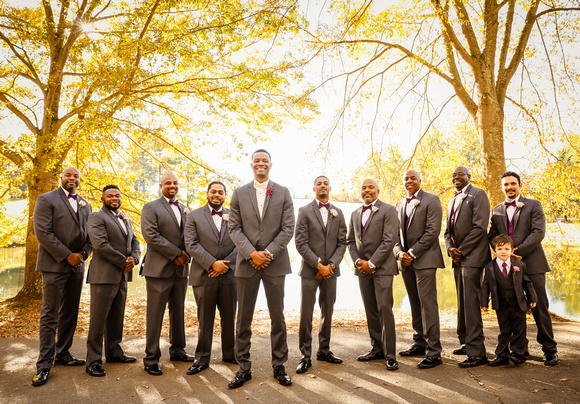 Wedding photography, the groom and groomsmen stand in front of bright yellow trees. 