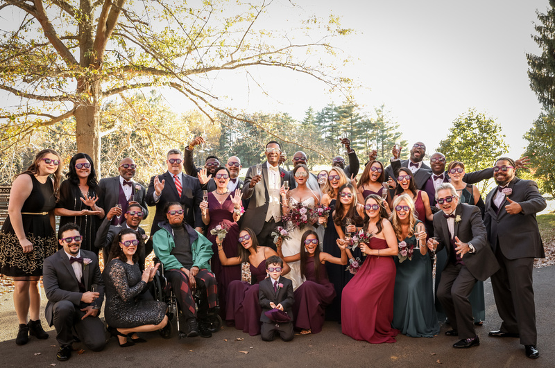 Wedding photography, a group celebrates with a toast and purple bride and groom sunglasses. 