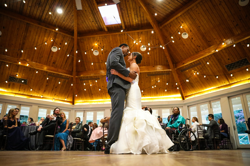 Wedding photography, the bride and groom embrace during their first dance under a wooden ceiling. 