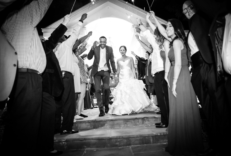 Wedding photography, a black and white image of the bride and groom running under a tunnel of sparklers. 