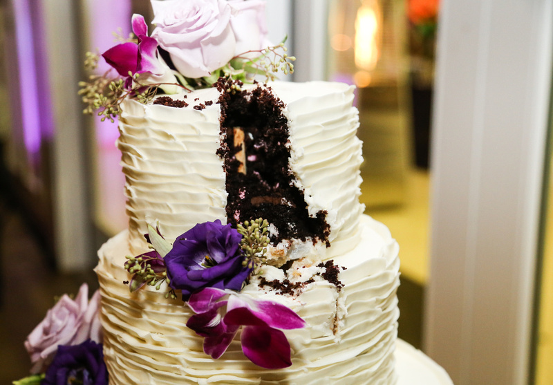 Wedding photography, a slice cut out of a chocolate cake with vanilla frosting and purple flowers. 