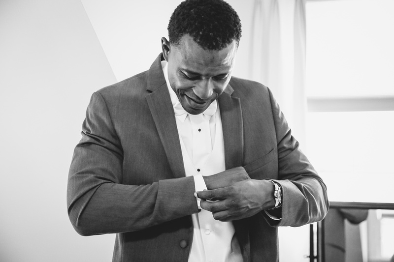 Wedding photography, a black and white image of a groom putting on his cufflinks. 