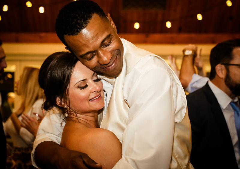 Wedding photography, the bride and groom embrace and smile with their eyes closed, while slow dancing on the floor. 