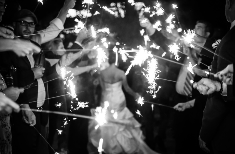 Wedding photography, a black and white image of guests holding out sparklers after the bride and groom have run through. 