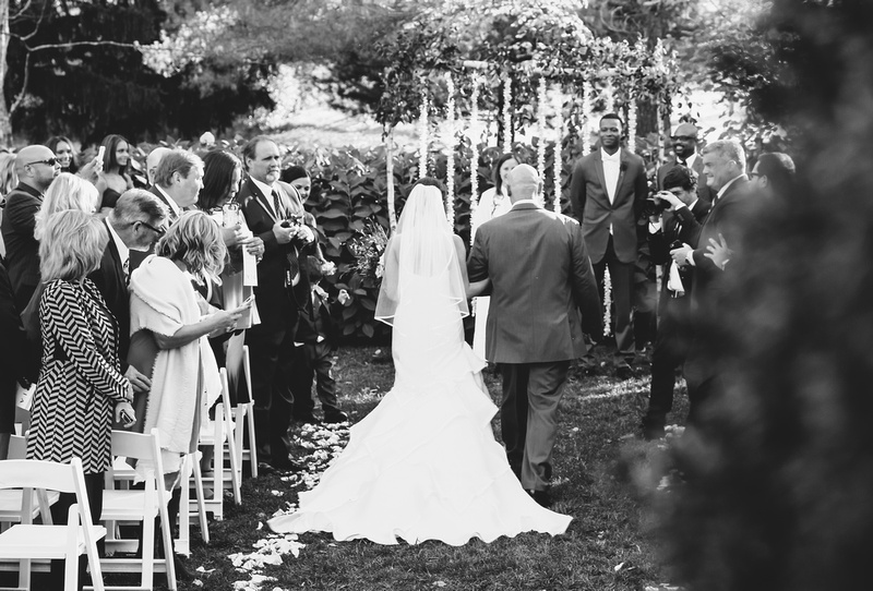 Wedding photography, a black and white image of a bride and her father walking down the aisle. 