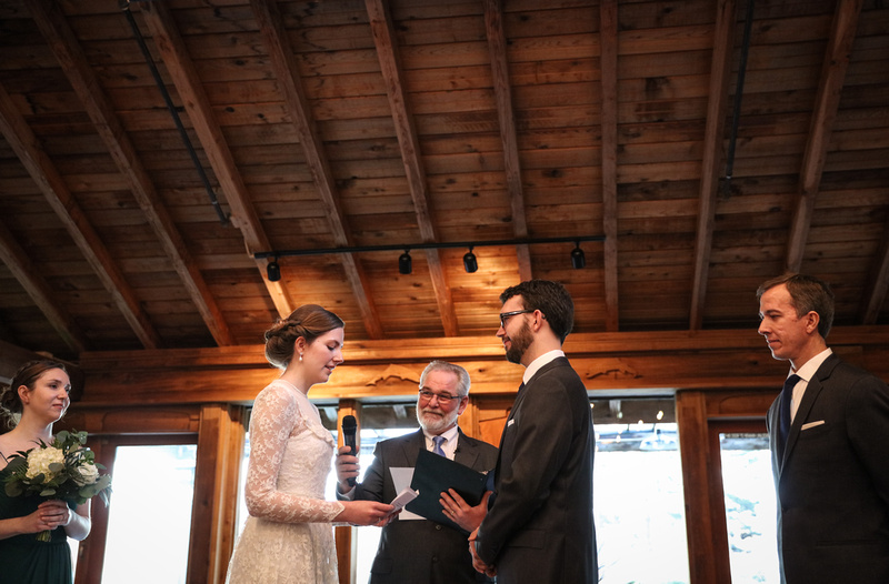 Wedding photography, a bride in a lace gown says her vows in a log cabin. 