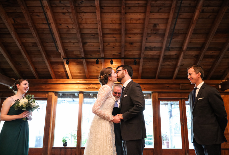 Wedding photography, a bride and groom share their first kiss in a log cabin venue. 