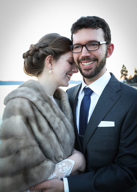 Wedding photography, a groom holds a bride tightly as she puts her forehead on him. She wears a fur stole. 