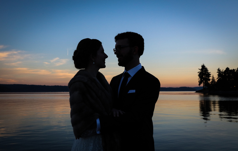 Wedding photography, a silhouette shot of a couple gazing at each other with blue and pink light behind them. 
