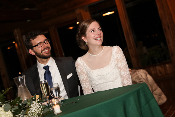 Wedding photography, the bride and groom smile at their green table during toasts. 