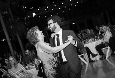 Wedding photography, a groom laughs while dancing with his mother. 