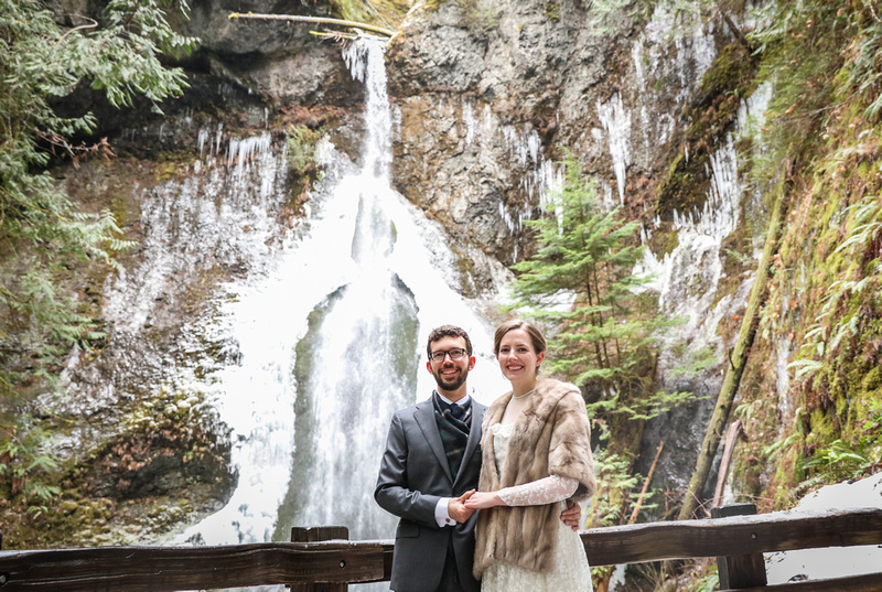 Wedding photography, a bride and groom stand in front of a waterfall. 