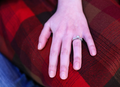 Wedding photography, a woman's hand, with an engagement ring, on her red plaid skirt. 