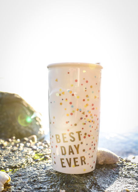 Wedding photography, a mug that says "Best Day Ever" sits on a rock by the water. 