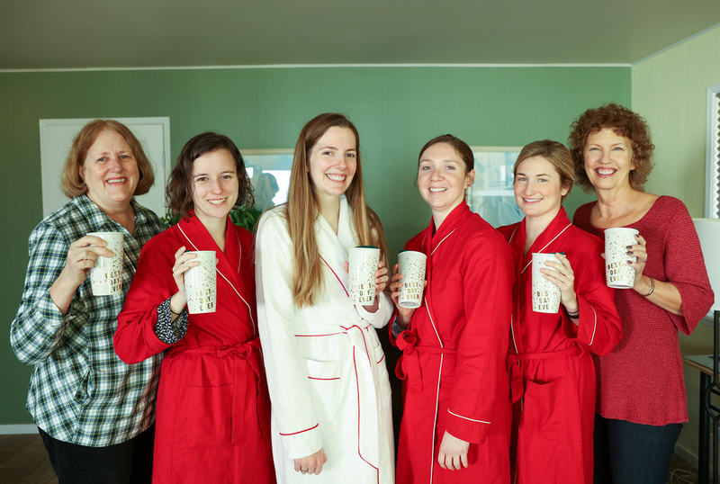 Wedding photography, a smiling wedding party poses in red robes with matching mugs. 