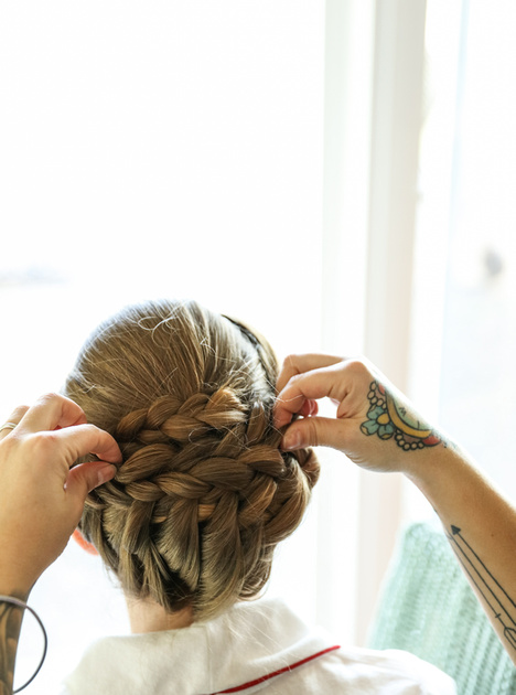 Wedding photography, a hairstylist with colorful tattoos fixes a bride's hair. 