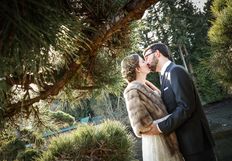 Wedding photography, a bride and groom share a romantic kiss under a tree. 