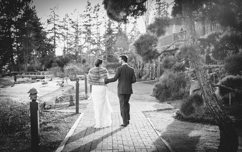 Wedding photography, a bride and groom walk away down a tree-lined path. 